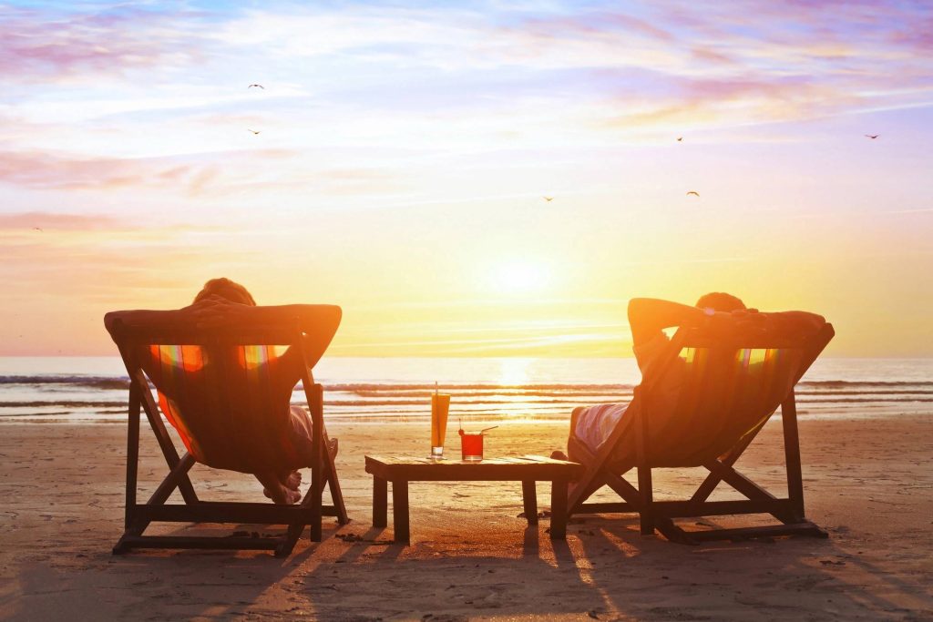 Two people sitting on deckchairs looking out at the sunset this gives yo a view of what could be generated by residual income from becoming a travel business owner, time freedom, residual income earn while everywhere an anywhere. 